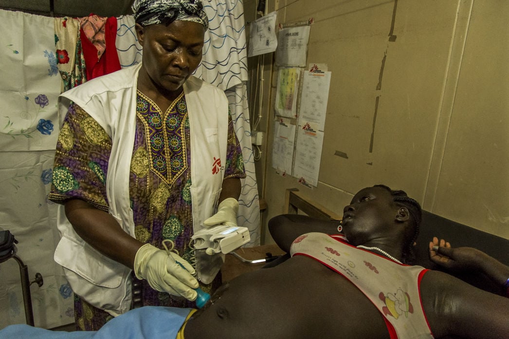 Florence, the MSF medical officer at the Old Fangak hospital in South Sudan, examines a worried pregnant woman who arrived in the evening in the maternity ward. Photo by Frederic Noy.