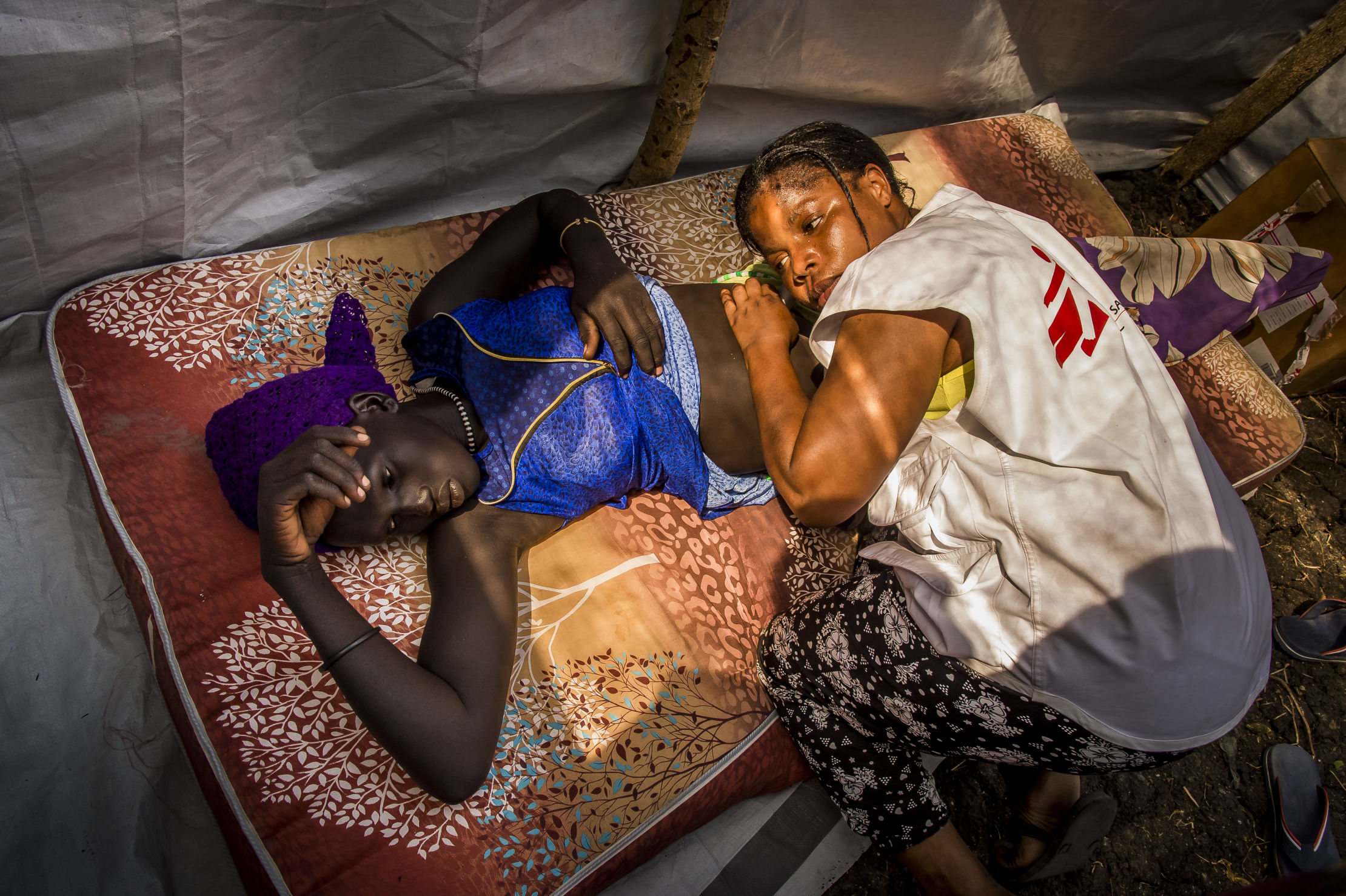 L'infirmière et sage-femme Furaha Bazikanya examine une jeune femme enceinte dans l'un des deux espaces de consultation d'une clinique mobile du village de Kier, au Soudan du Sud. Photo : Frederic Noy/COSMOS.